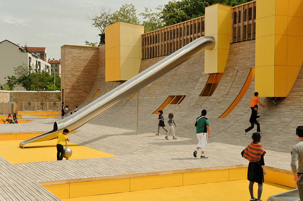 Overview of play structure showing sloping wood deck and tube slide