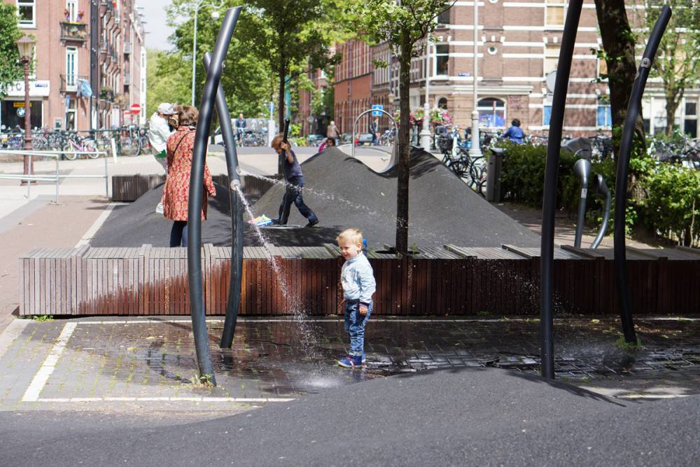 Little boy plays among water-spraying elements