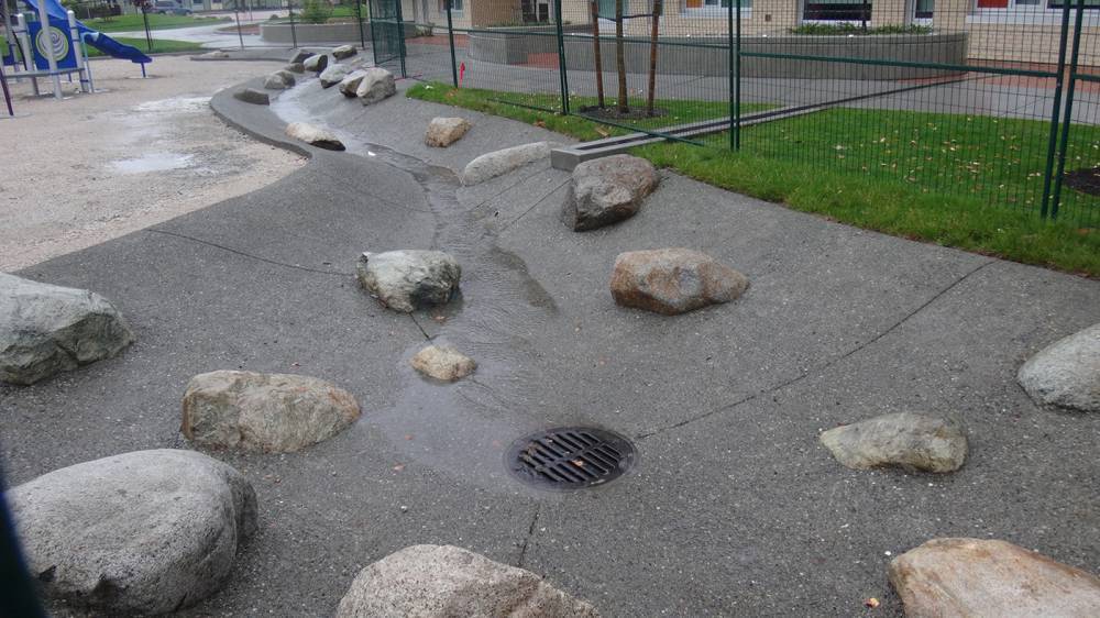 Boulders integrated into a poured rubber swale