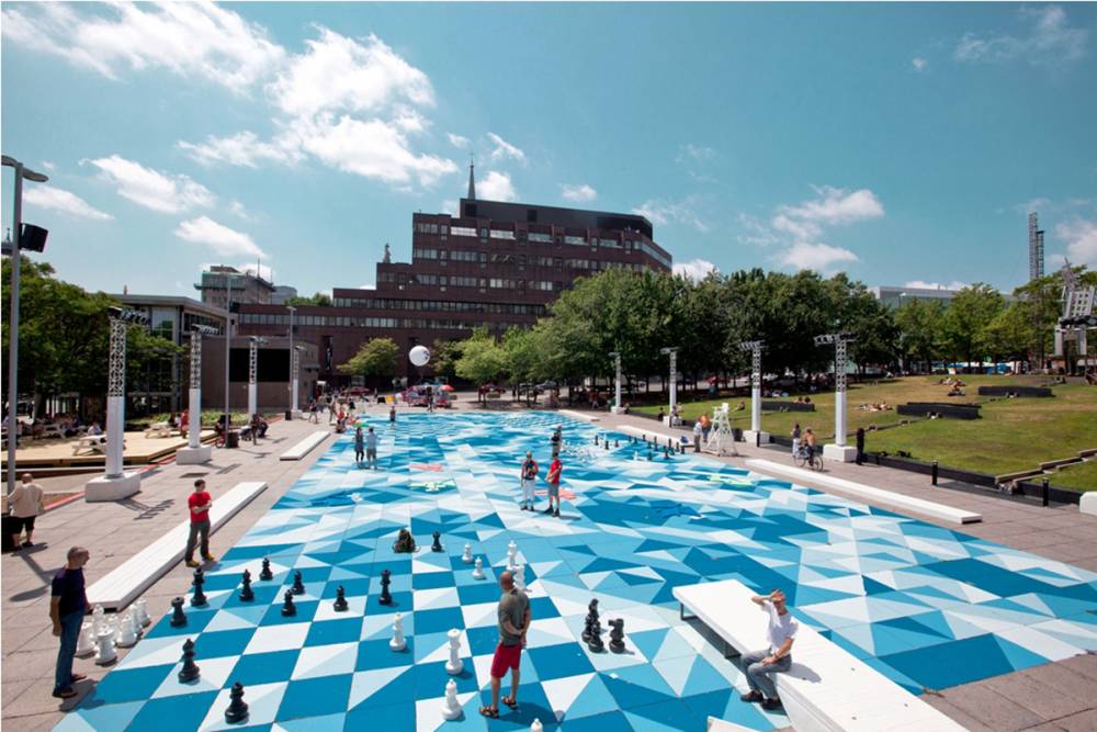 A game of giant chess takes place on painted concrete pavers