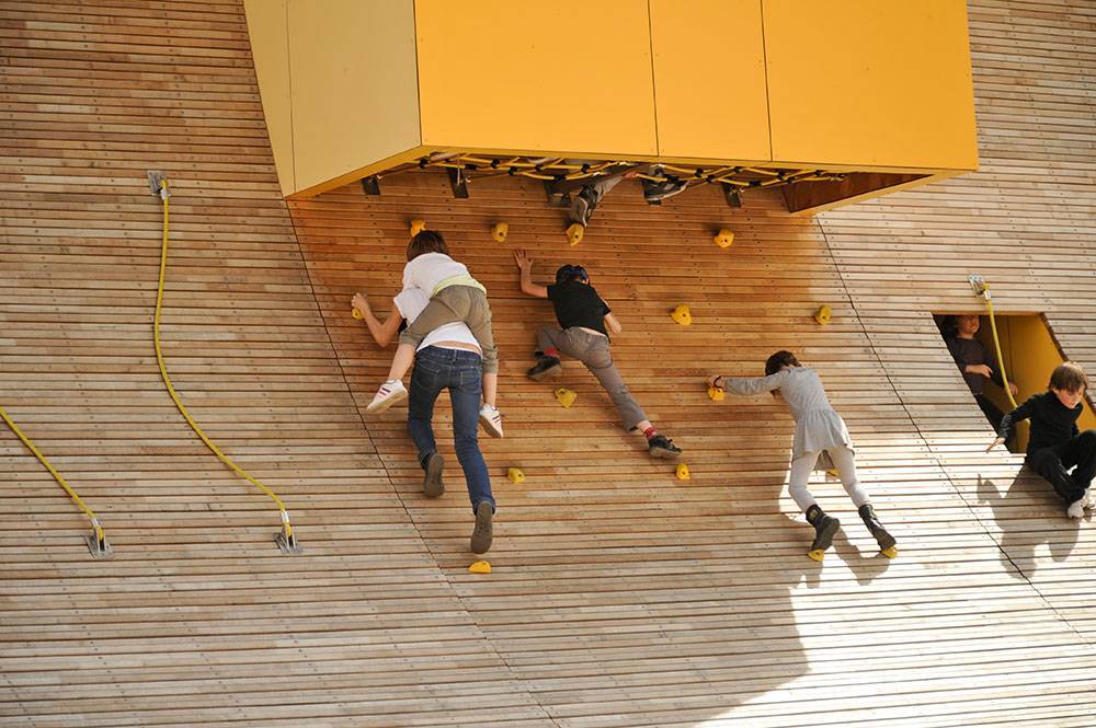 Yellow climbing holds mounted on a curved wood wall
