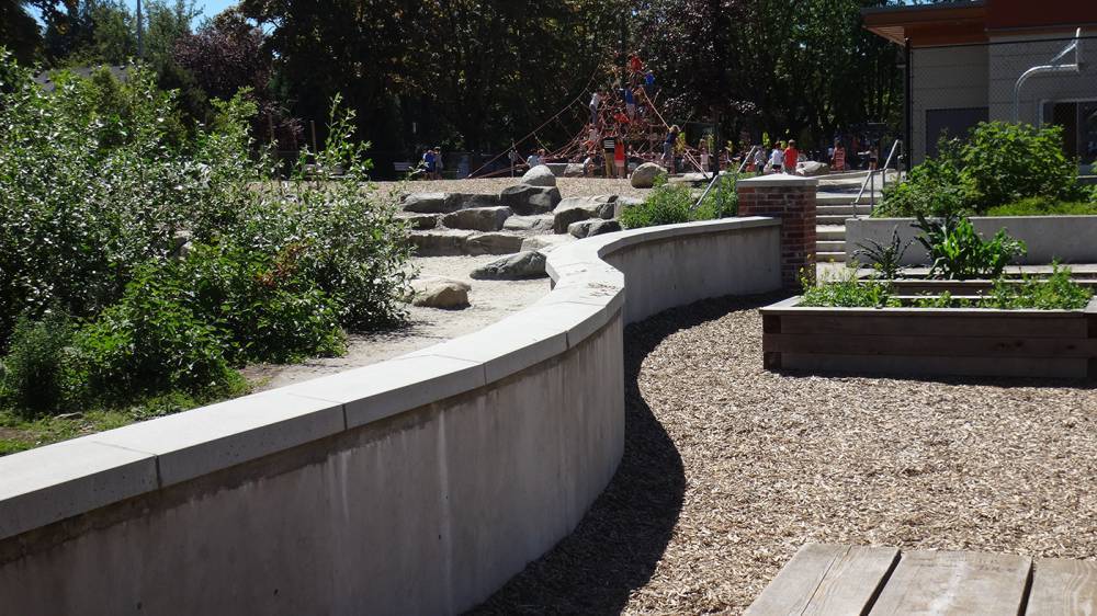 A freestanding wall divides the community garden and play areas