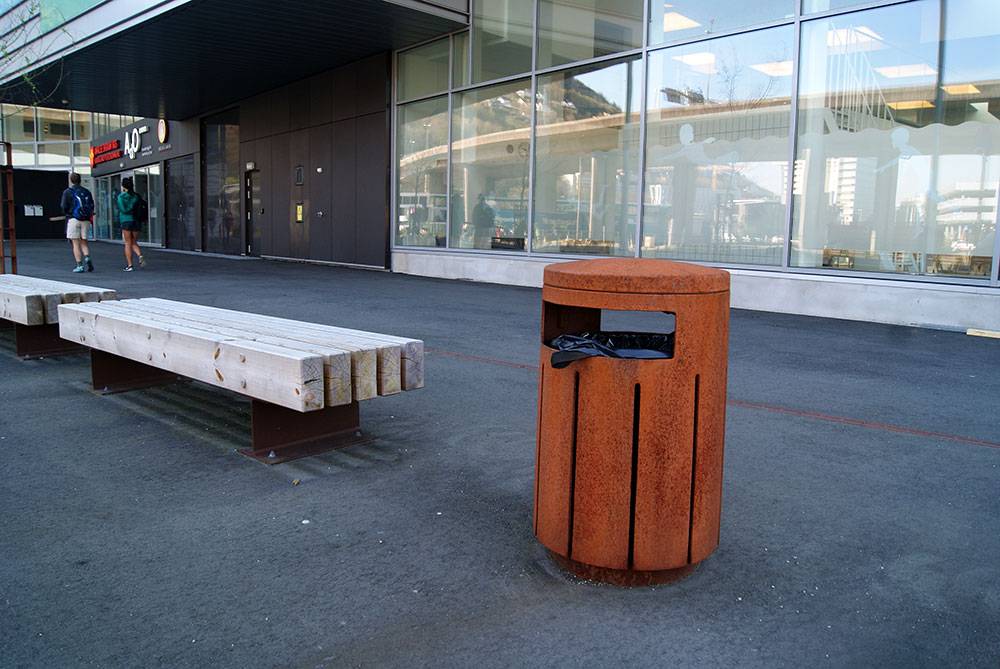 Metal garbage can conveniently close to benches