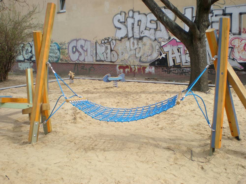 A brightly coloured hammock swing is suspended between wooden beams