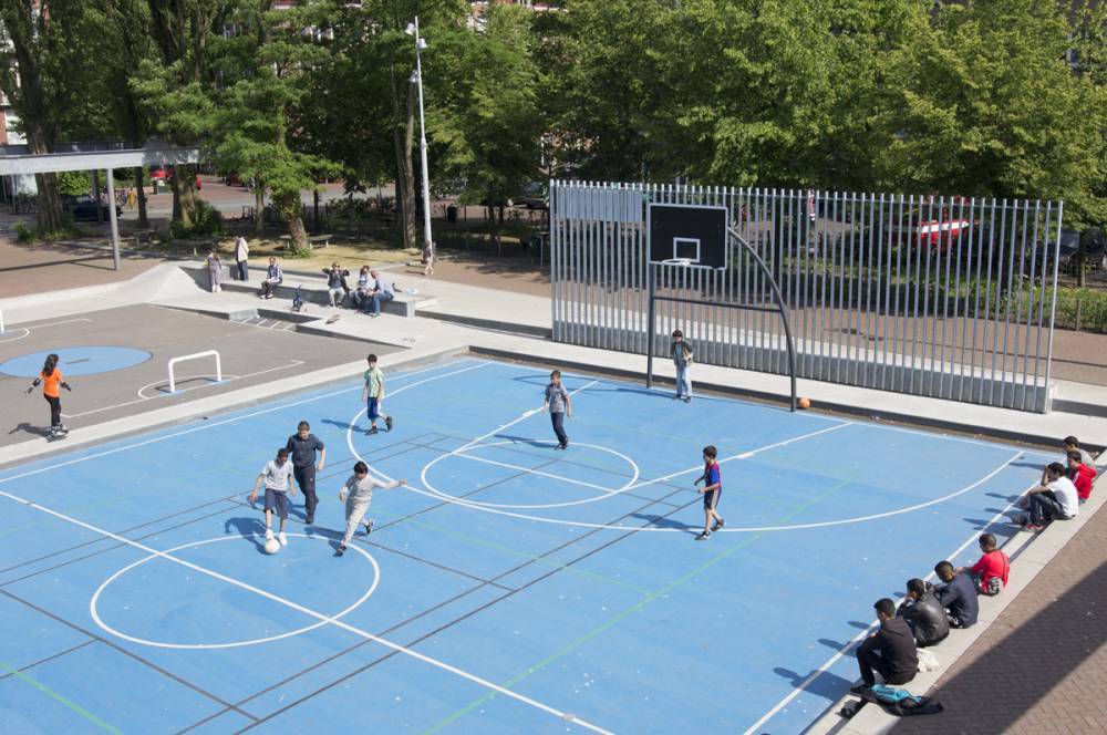 A tall metal wall helps to catch balls that miss the net at this sport court
