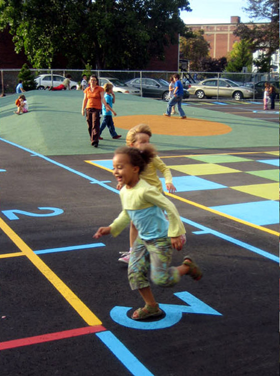 Children playing on painted asphalt with mound in the background