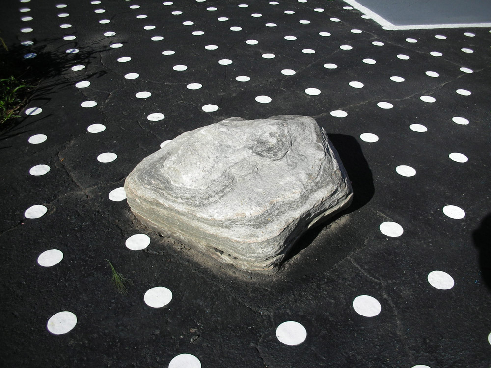Embedded boulder in asphalt painted with dots