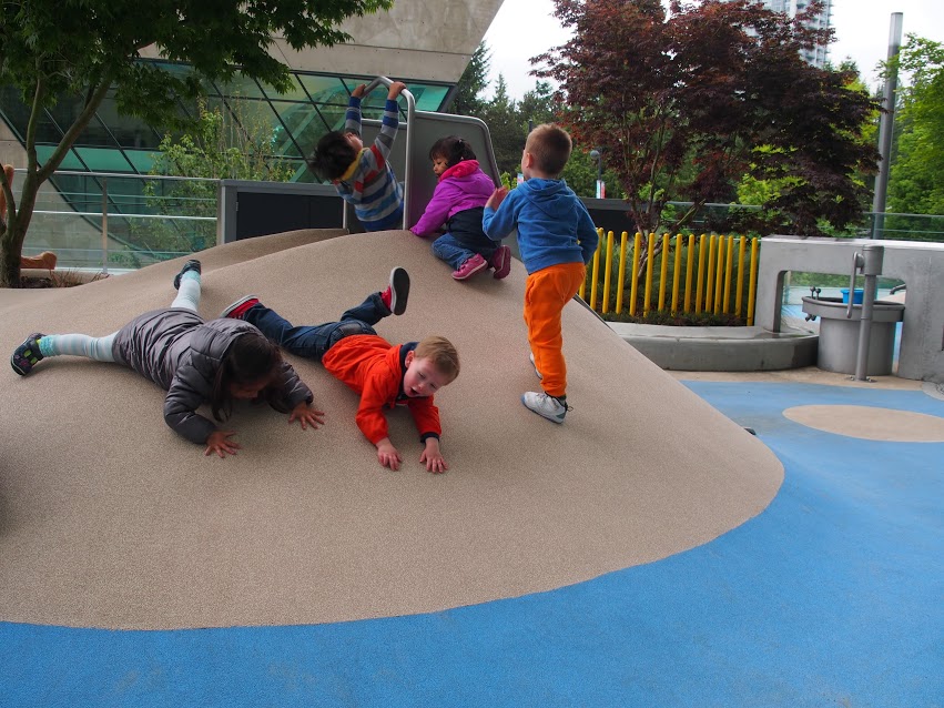 Children play on rubber mound with an integrated slide