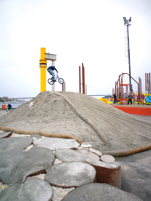 A BMX ride gets airborne above sand mound
