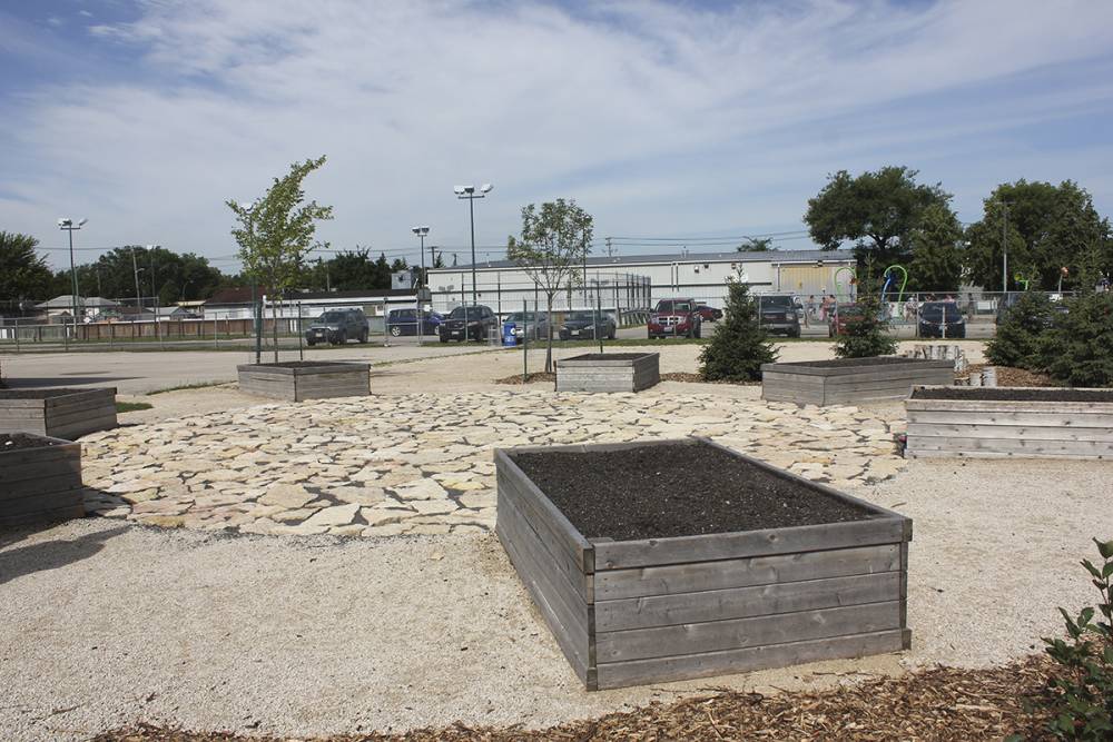 Raised planter beds awaiting edible planting, surrounding a circular stone paver area