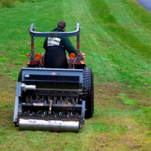 Rolling an aerating machine over compacted lawn